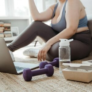 Plus size woman exercising at home with purple dumbbells, showcasing healthy lifestyle.